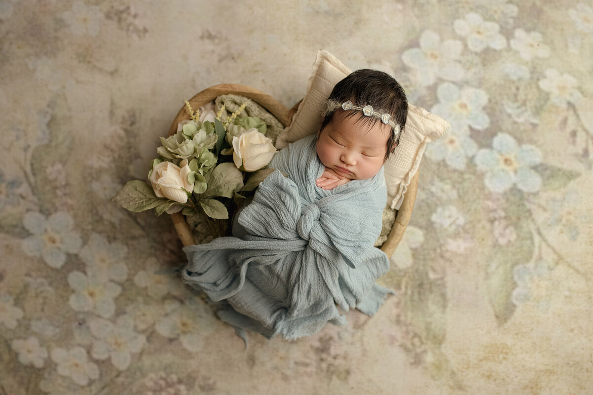 Newborn girl wrapped in blue bow blanket