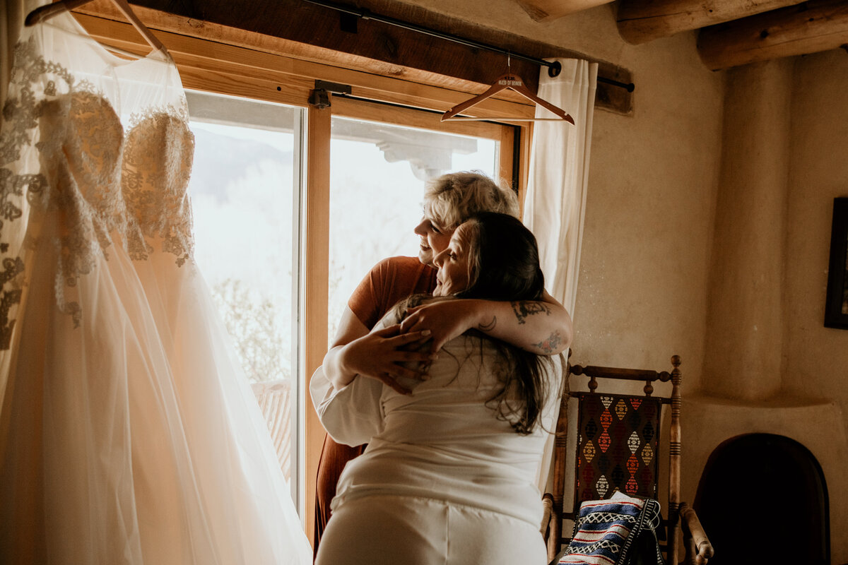 sisters hugging before putting on bridal gown