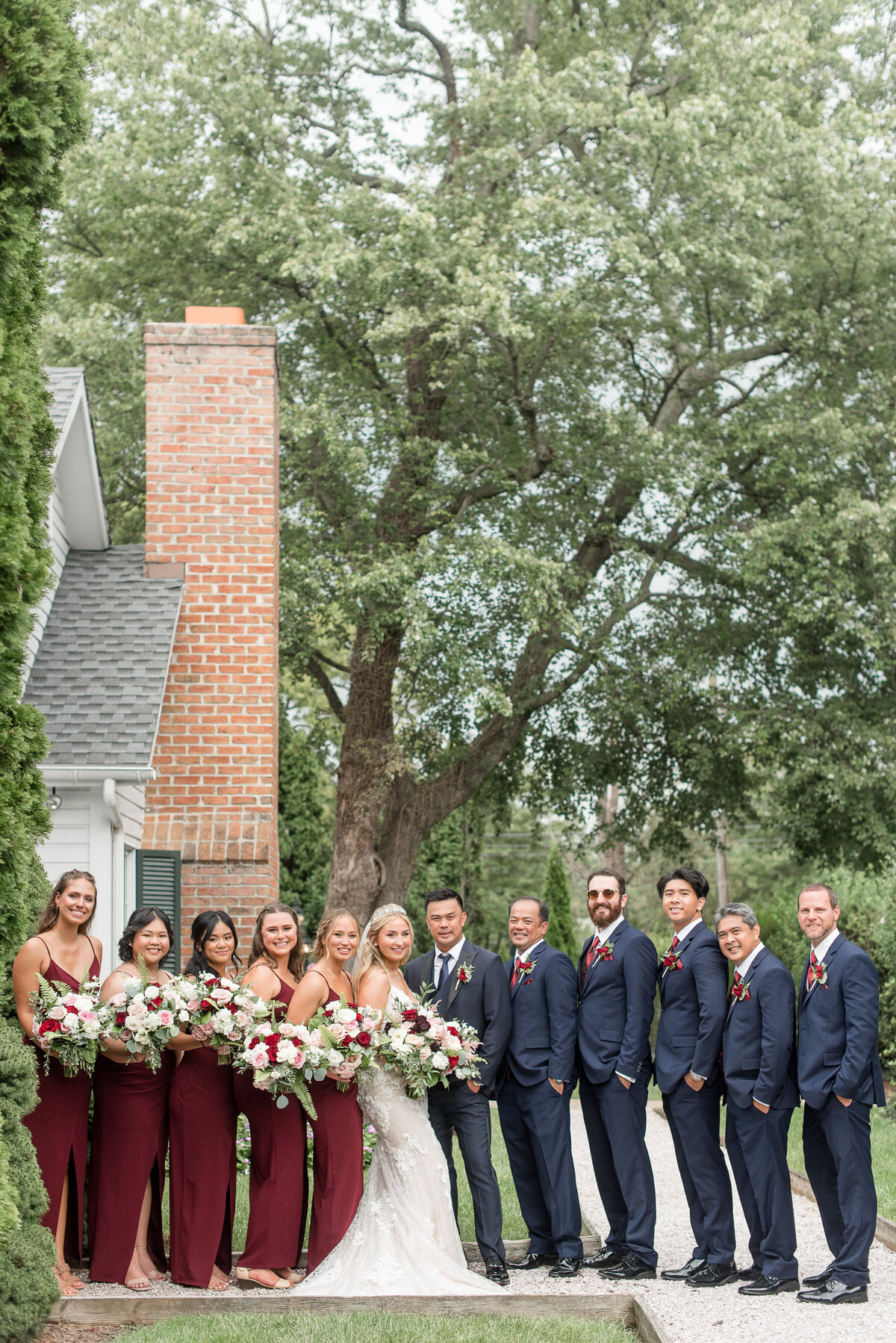 Bride and Groom standing close with their bridal party lined up on either side of them by house at Antrim 1844 in Maryland.