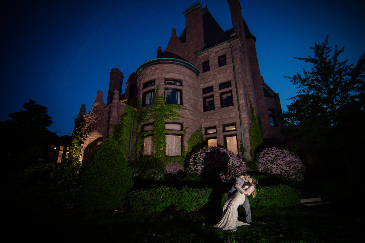 Bride and groom kiss in front of Van Dusen Mansion in Minneapolis at night.