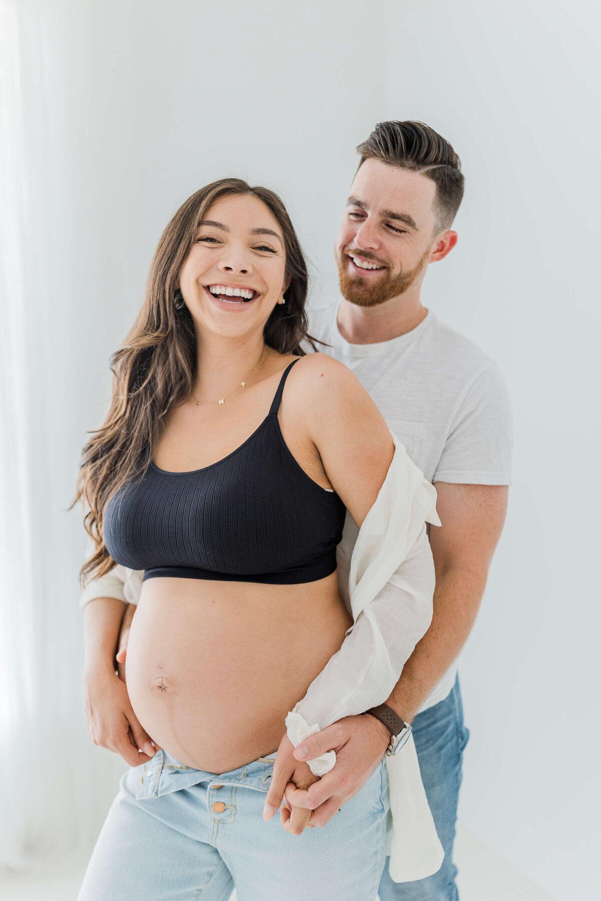couple standing together laughing during maternity photoshoot