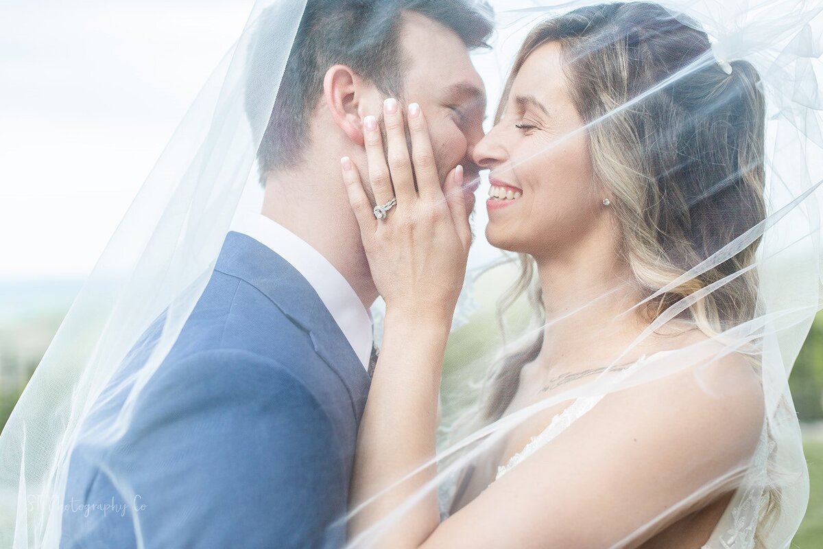 Bride and groom about to kiss under a veil