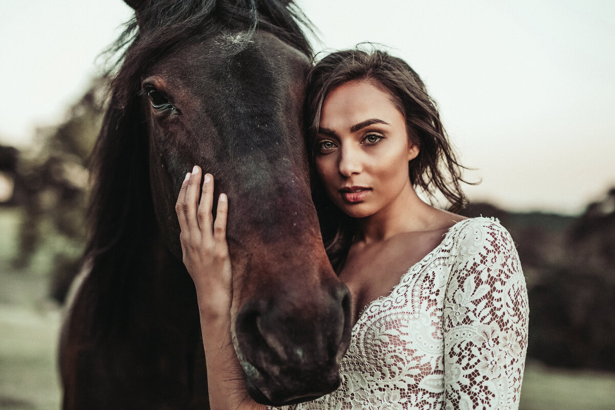 Bride stroking horse in her wedding dress