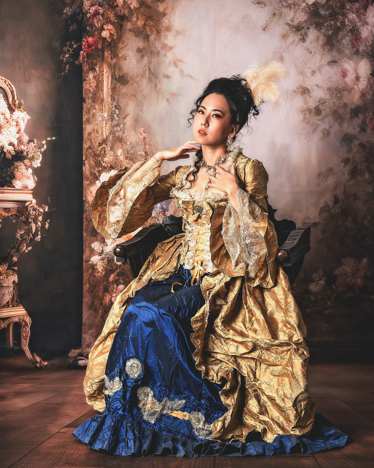 Fine art portrait of a woman in an opulent gold and blue Rococo gown inspired by 18th-century European fashion, photographed at AMM Fine Art Studio in Kirkland.