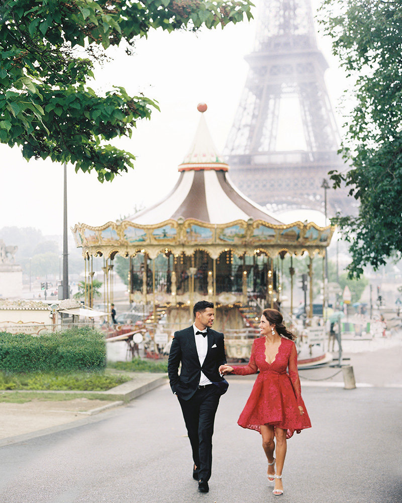Couple holds hands by carousel in Paris 19