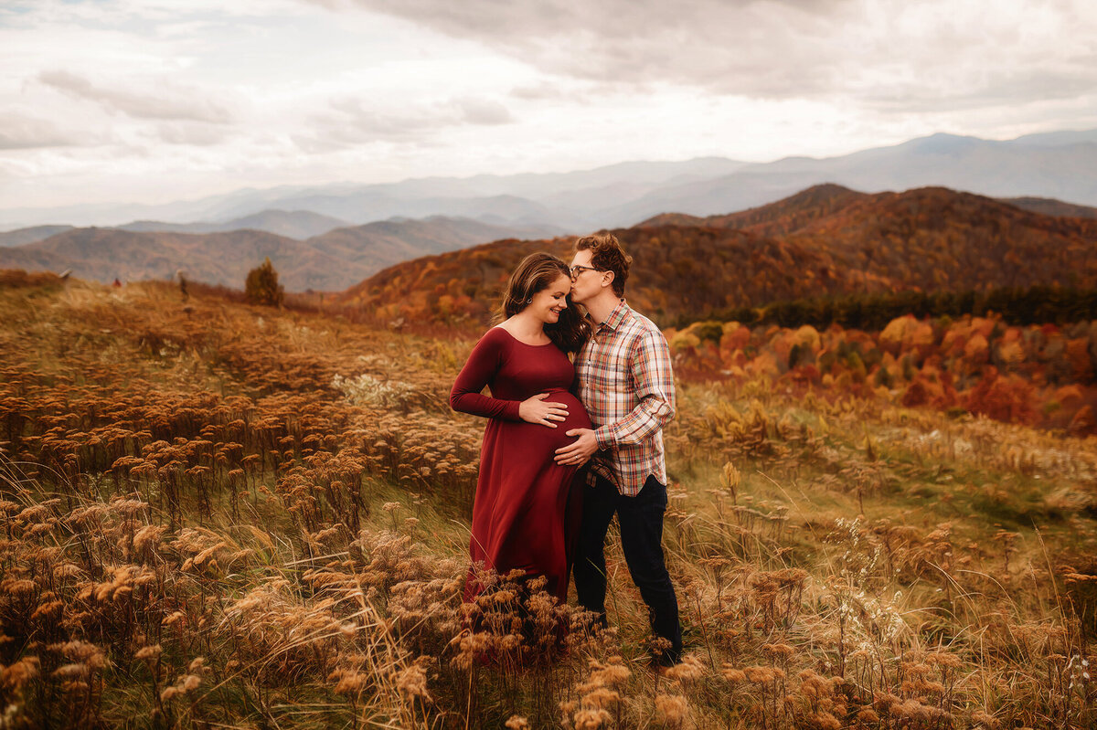 Parents kiss on a mountain top during Family Photoshoot at Max Patch in Asheville, NC.