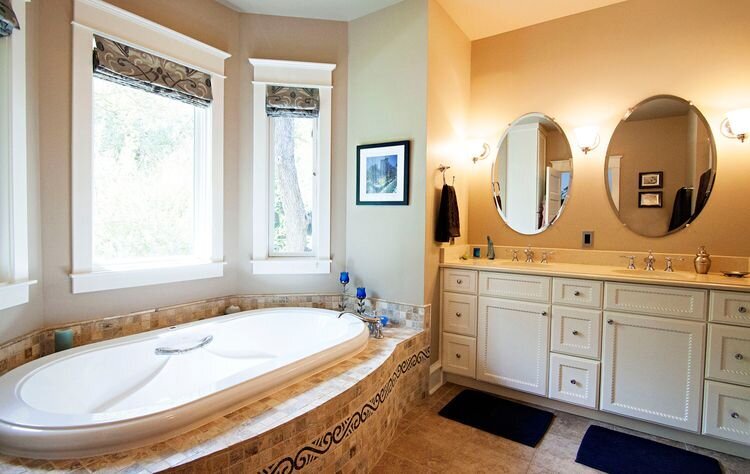 duoble sink in bathroom for husband and wife. stand-alone tub with big windows and white bathroom cabinets.