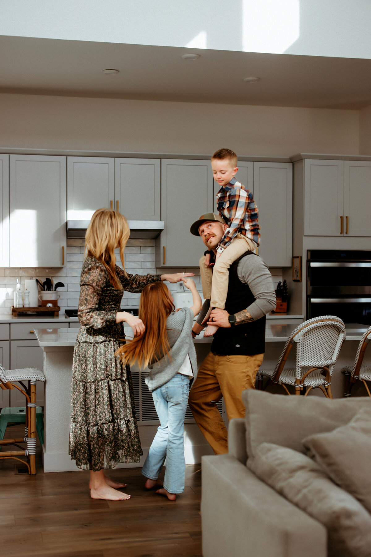 family playing in kitchen and getting piggy backs from parents for at home photo session