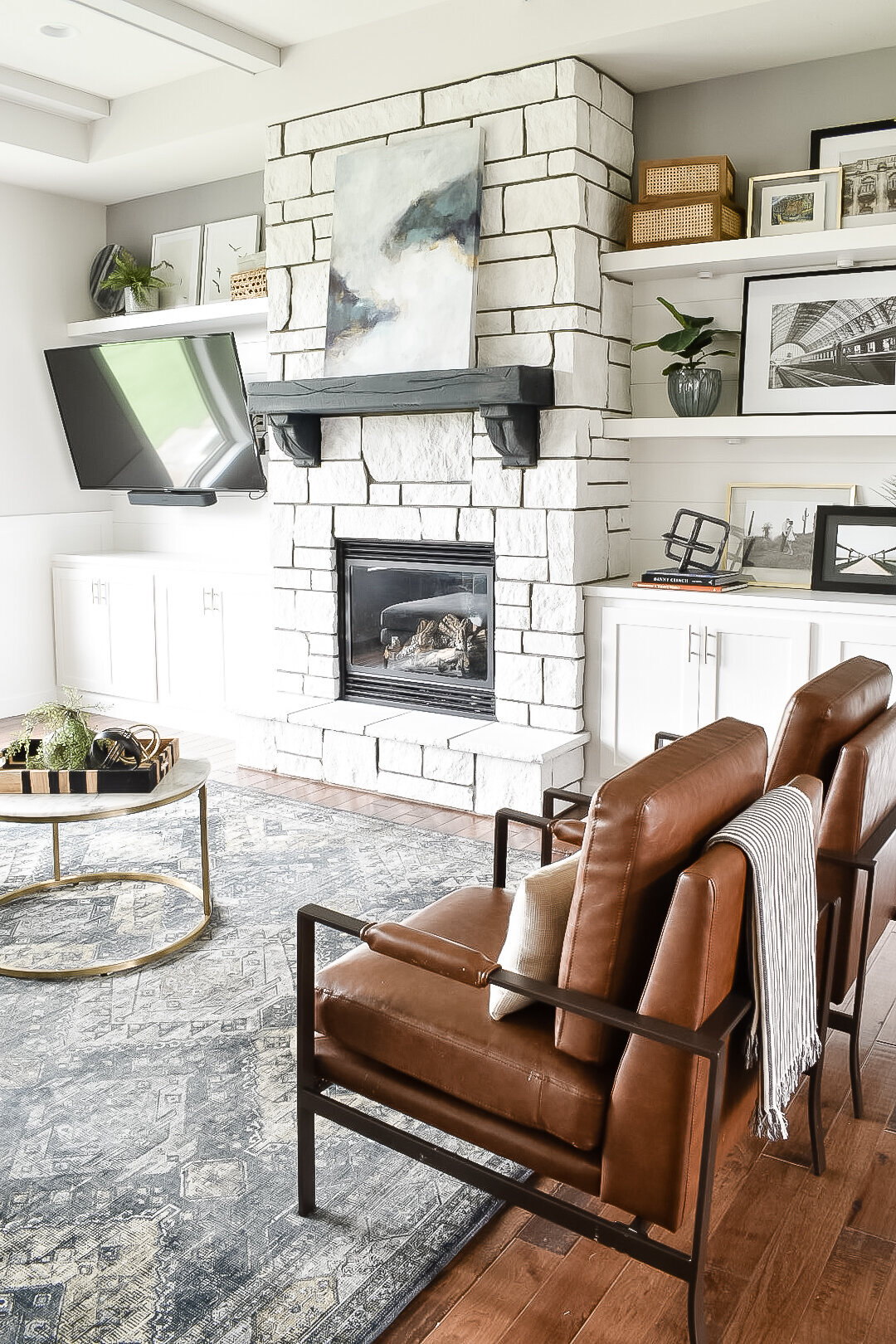Two modern industrial leather chairs sit side by side in a living room with large open shelves