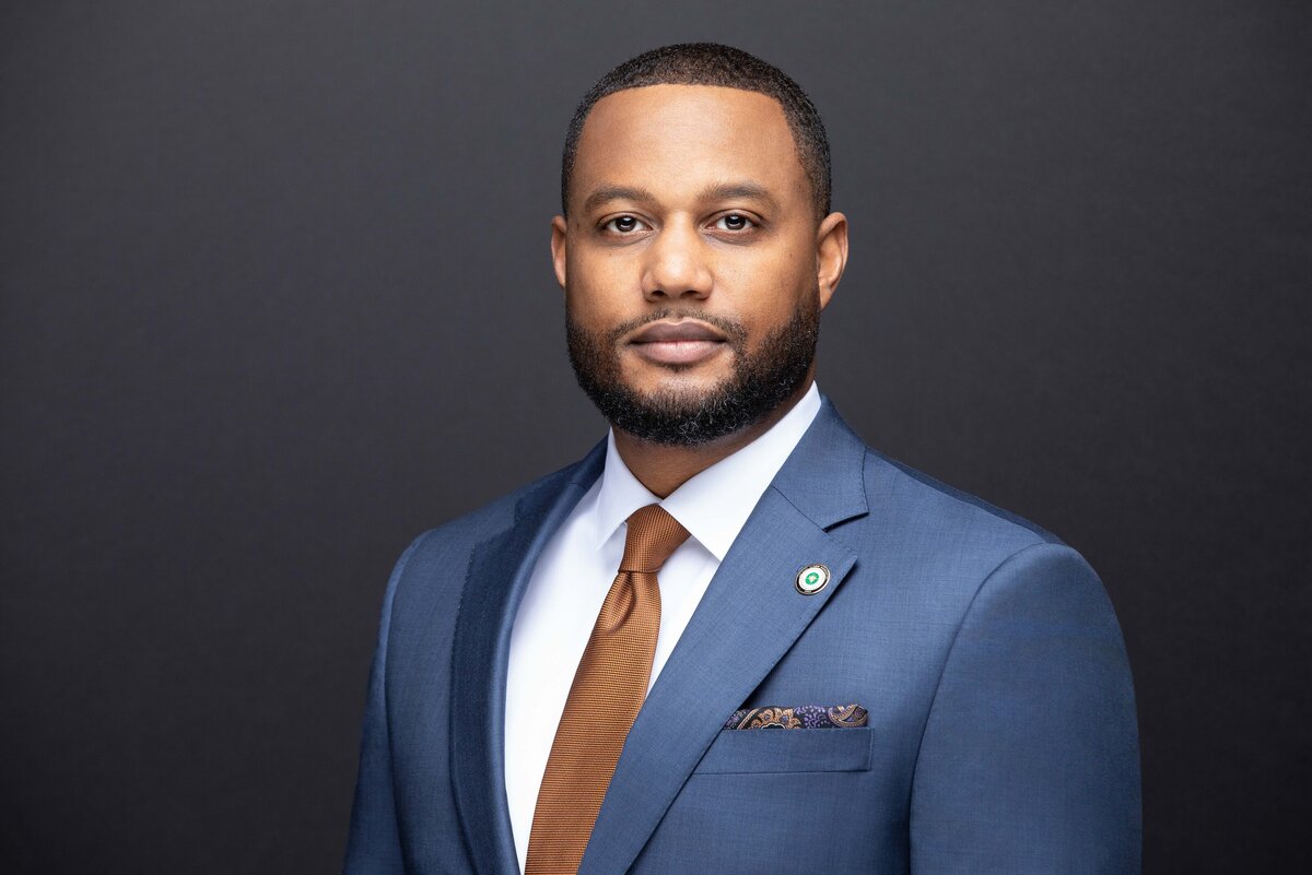 An African American black man and sales professional in a blue and gold tie suit poses for a professional headshot photo on location for Janel Lee Photography studios in Cincinnati Ohio