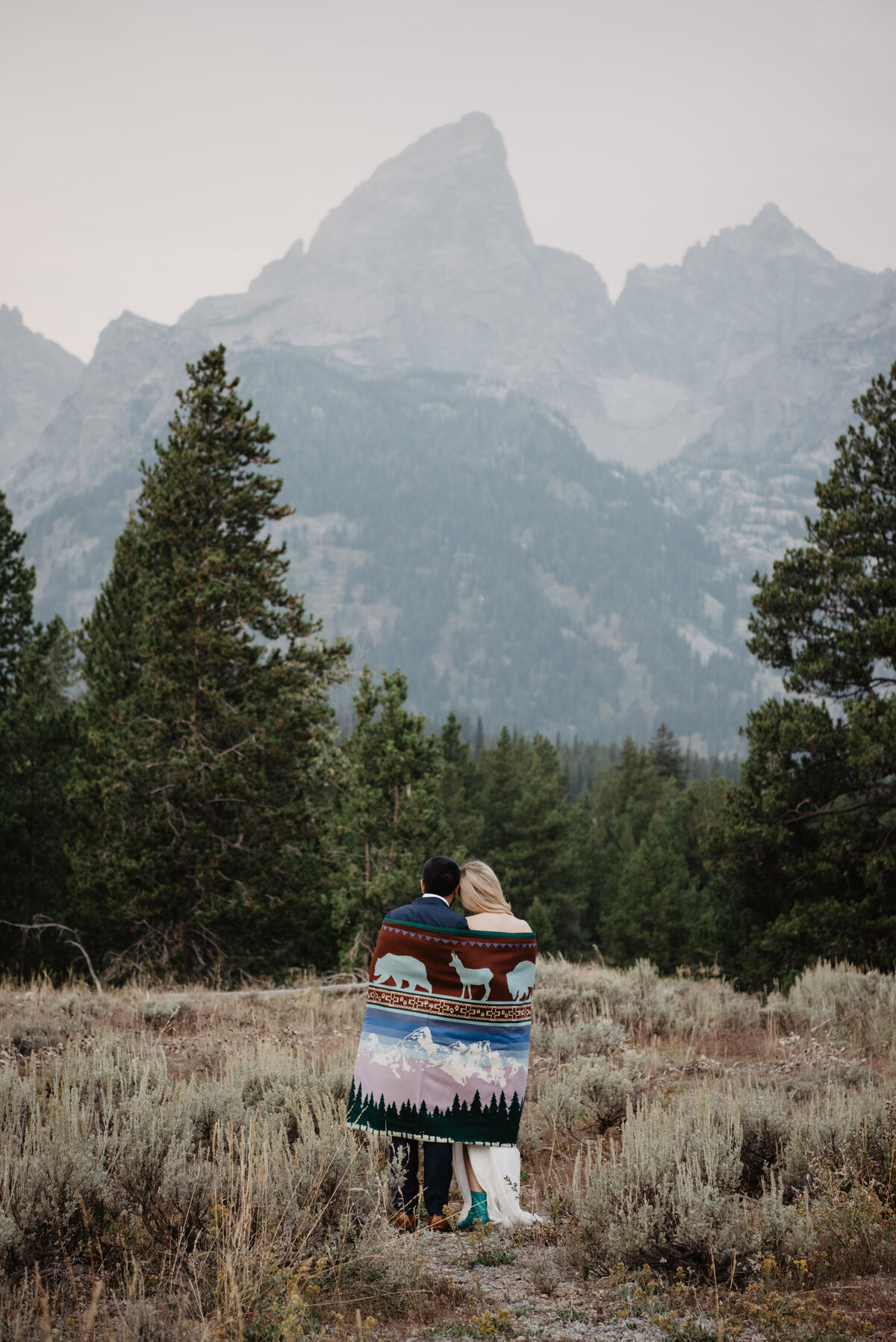 Photographers Jackson Hole capture bride and groom sharing a blanket