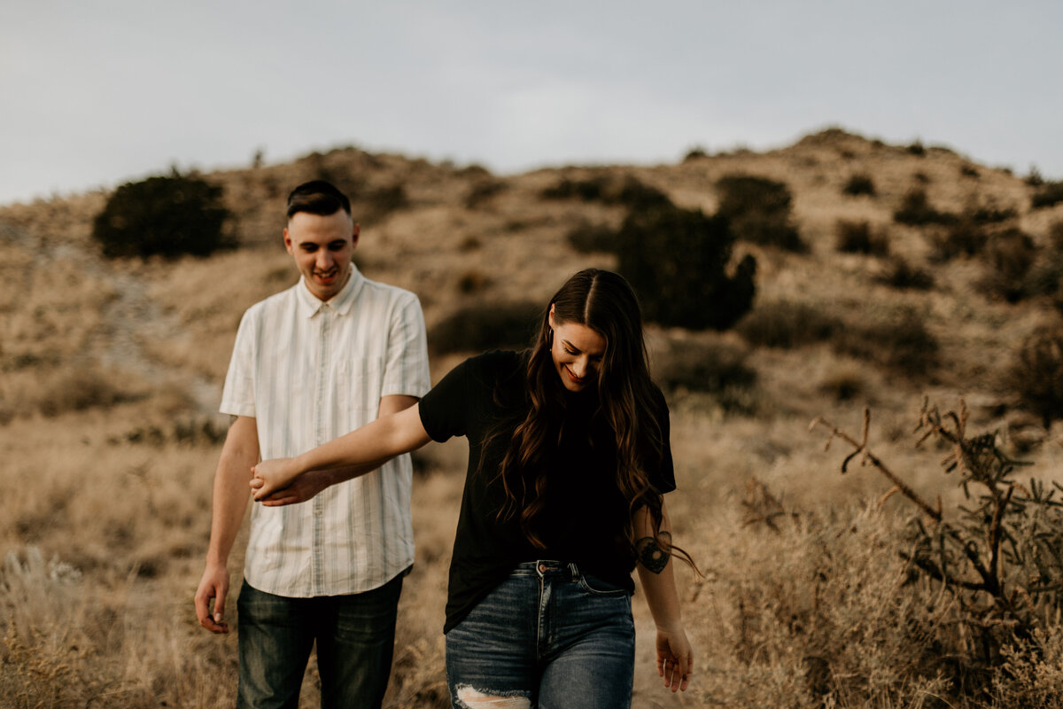 engaged couple holding hands and walking in the desert