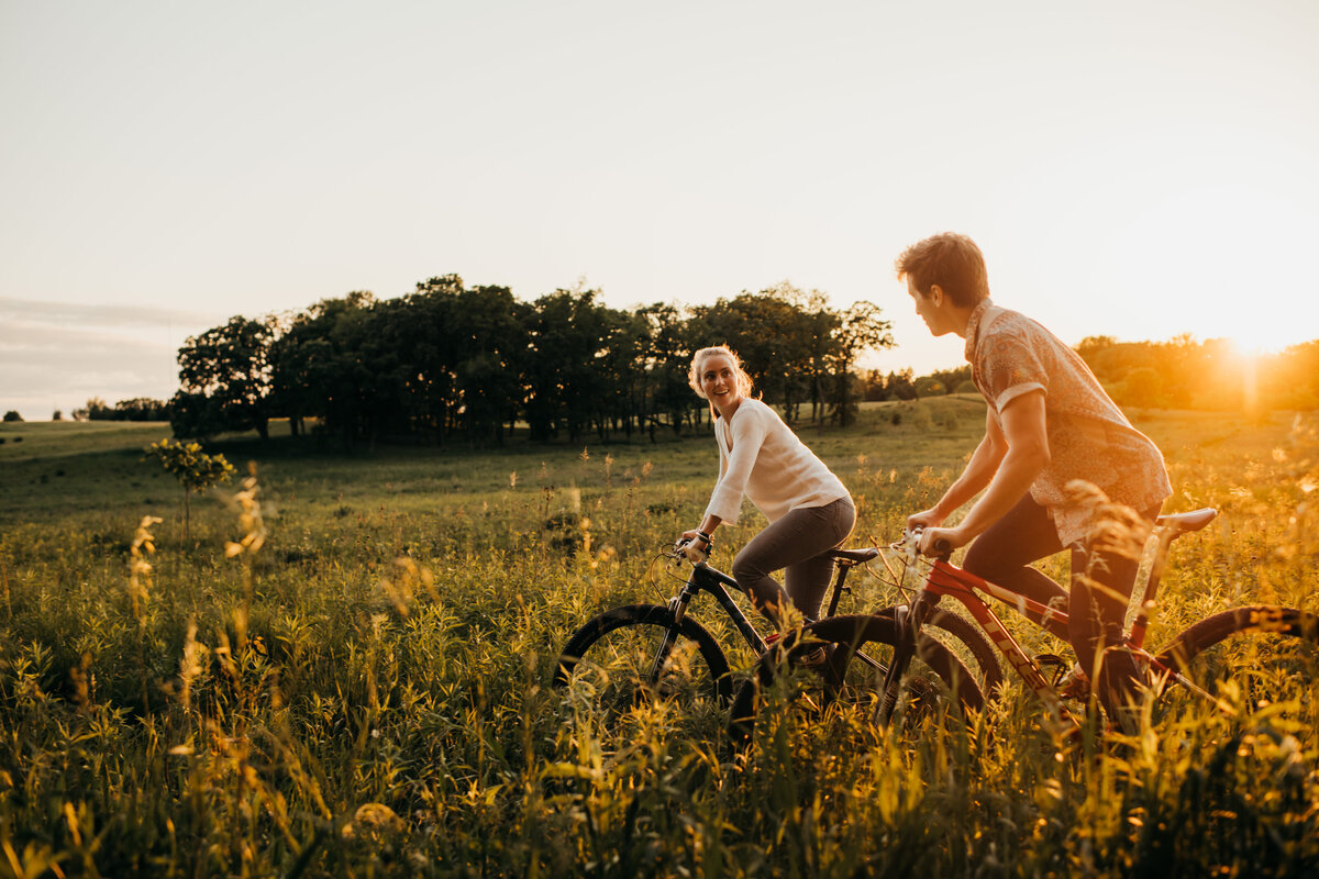 Man and woman riding their bike while the sun shines in the background