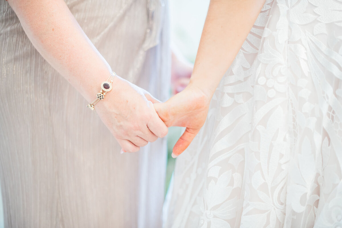 bride and her mother hold hands