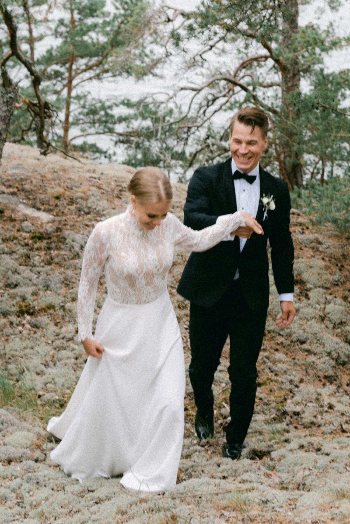 A wedding couple is laughing and walking in the forest in Finland. A wedding photograph by Finnish photographer Hannika Gabrielsson.