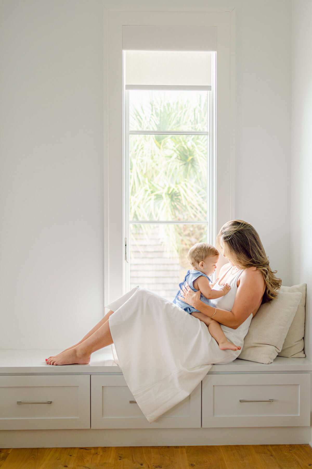 Light and Airy In Home Photography, with Mom on the Bed in a White Dress Taken by Charlotte Maternity Photographer.
