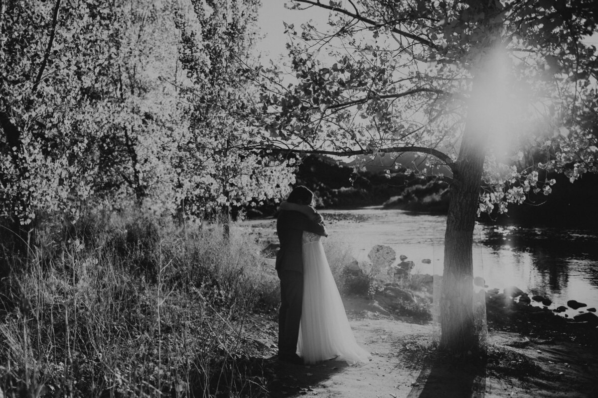 bride and groom hugging by a river