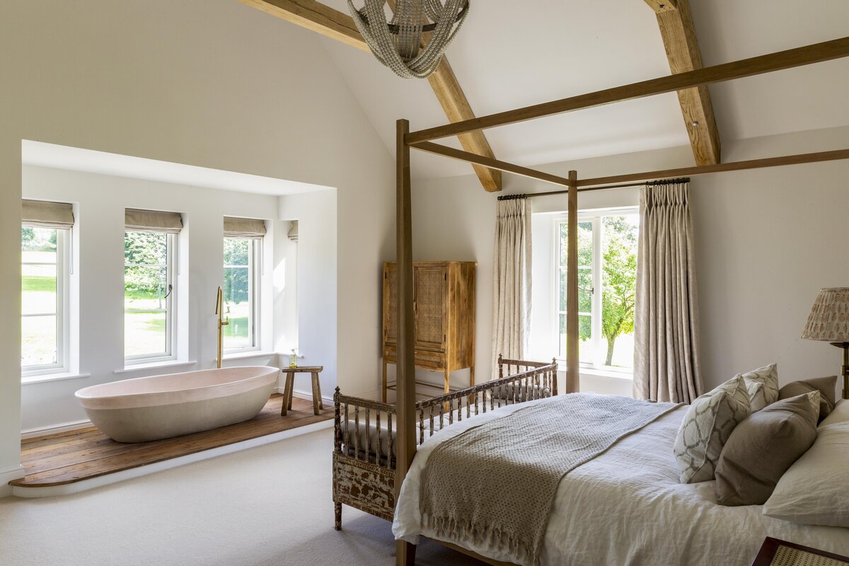 Master bedroom with freestanding bath in the window on a wooden floor