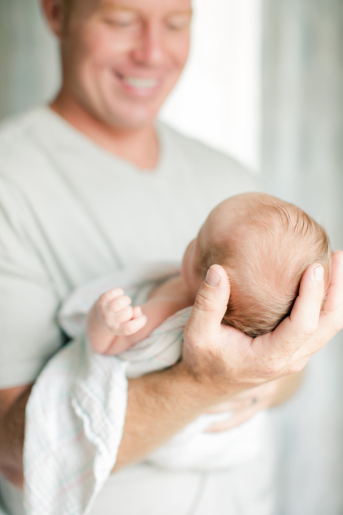 dad holds head of newborn baby in nursery for newborn photography