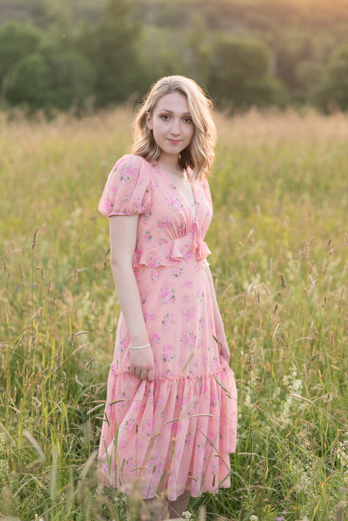 Girl in pink dress standing in field of tall green grass