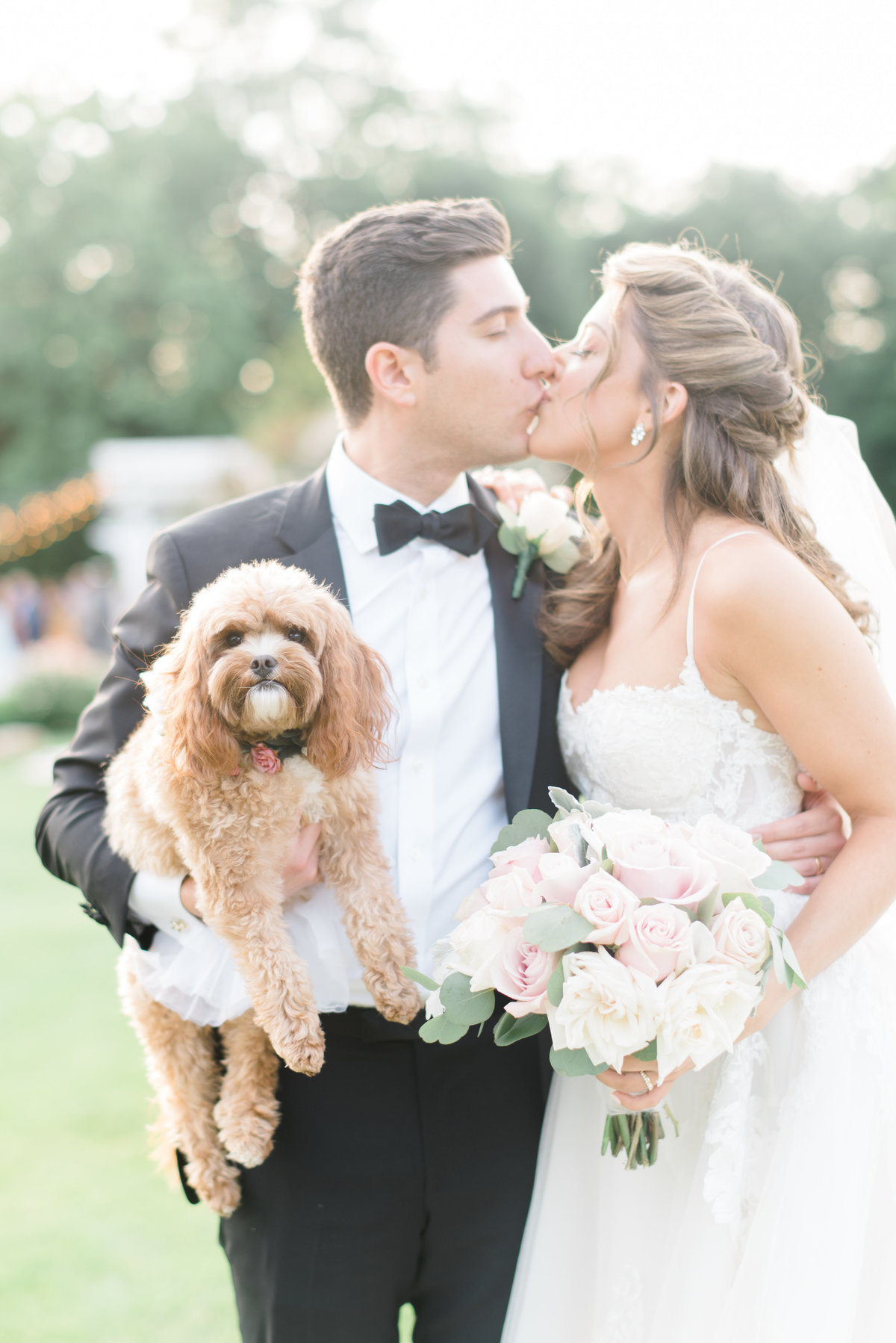 portrait-bride-and-groom-kissing-wit-groom-holding-dog
