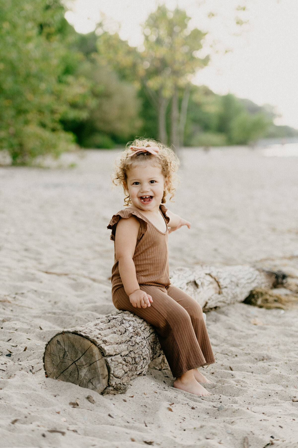 smiling girl on the beach on a log
