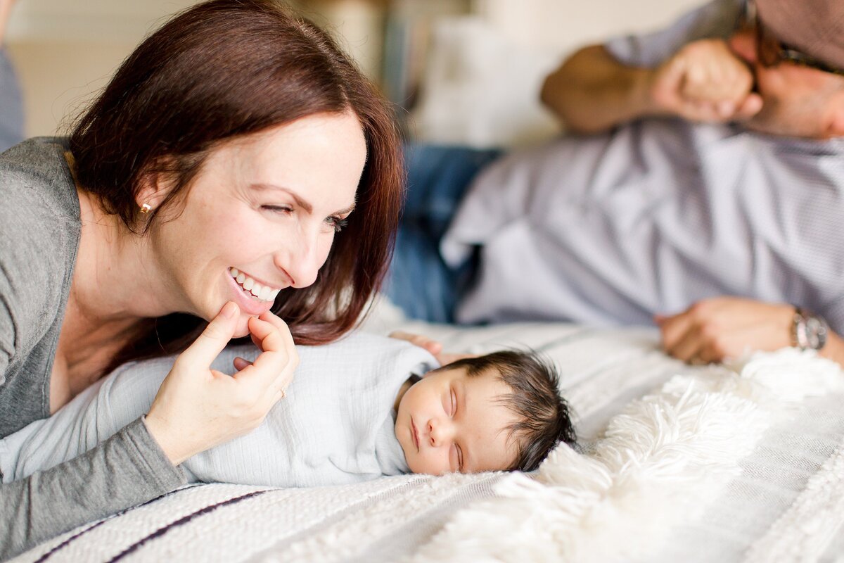 A mom and dad laughing with newborn.