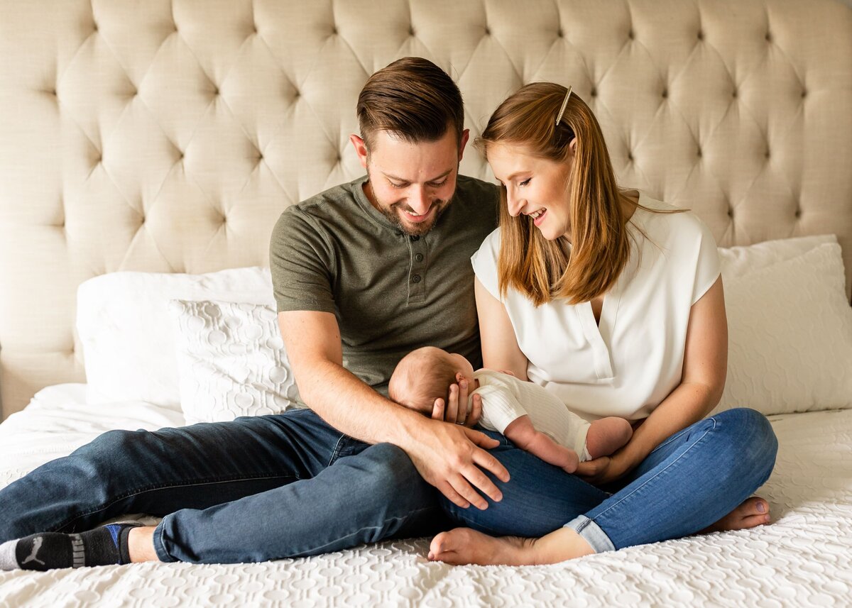 parents sitting on the bed with their newborn baby