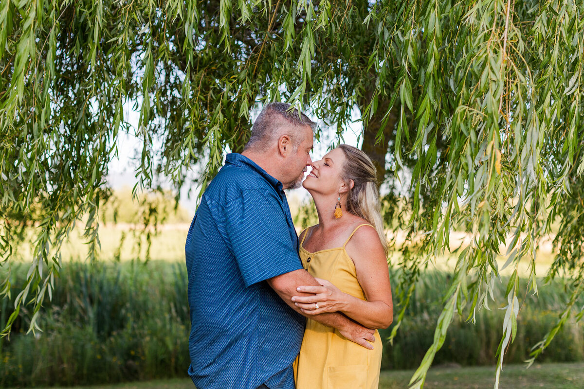 Engagement session in fields with willow tree Skagit county near Belliingham happy couple smiling and laughing colorful photo by Joanna Monger Photography