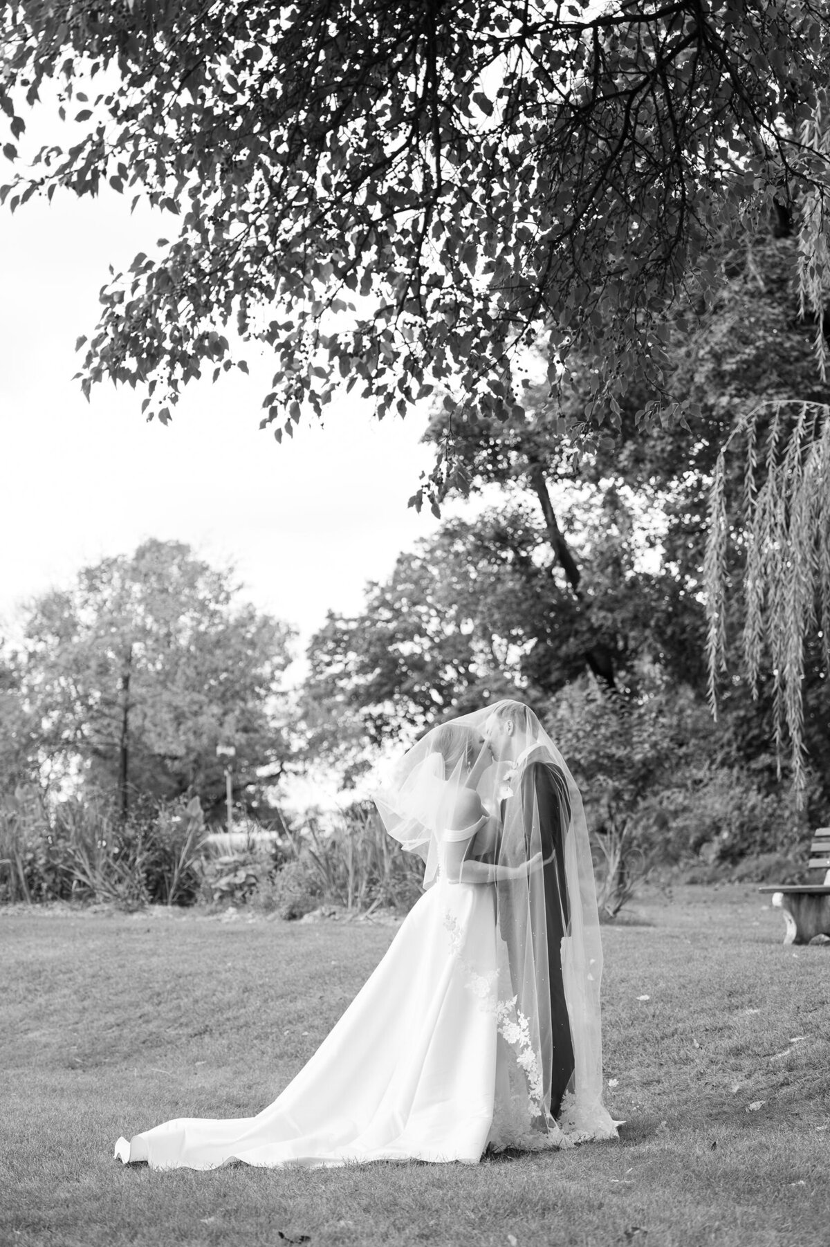 Bride and groom in park under veil