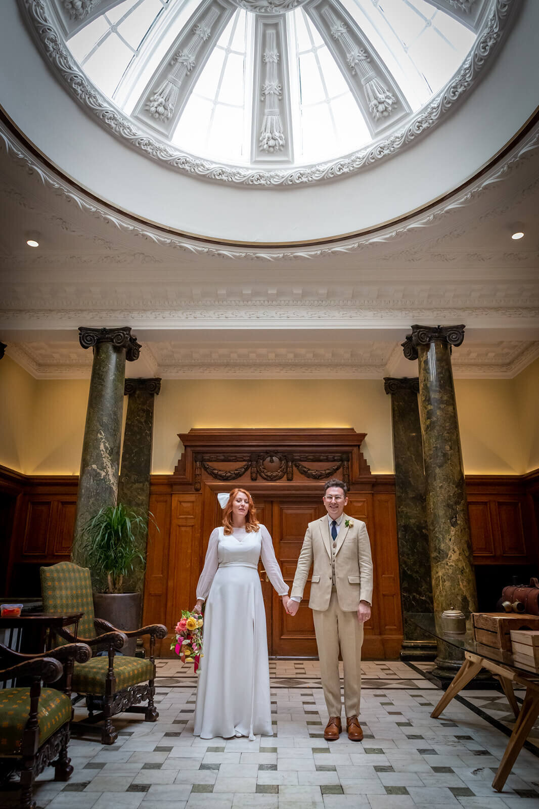 Bride and Groom standing hand in hand in Town Hall Hotel London