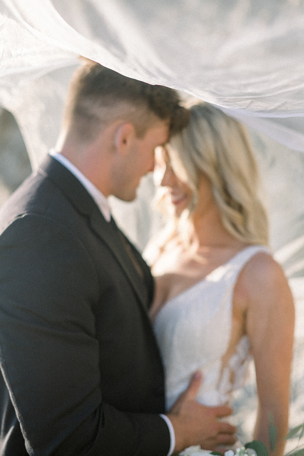 Bride and groom under veil at Dolphin Bay Resort in Pismo Beach, CA