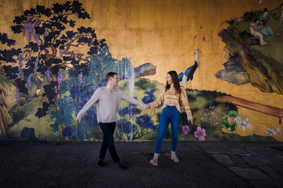 A couple dances in front of a yellow and flower mural in Chicago, IL