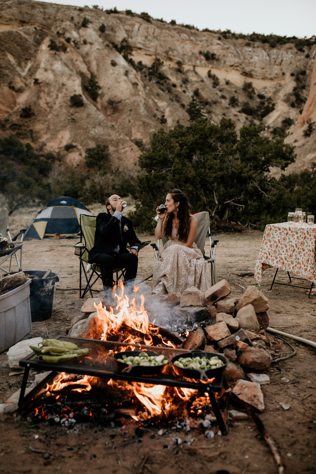eloping couple drinking at campsite fire