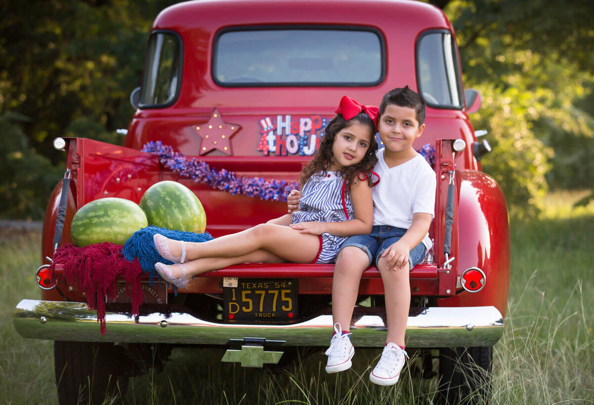 brother-sister-sitting-in-red-truck-with-watermelon