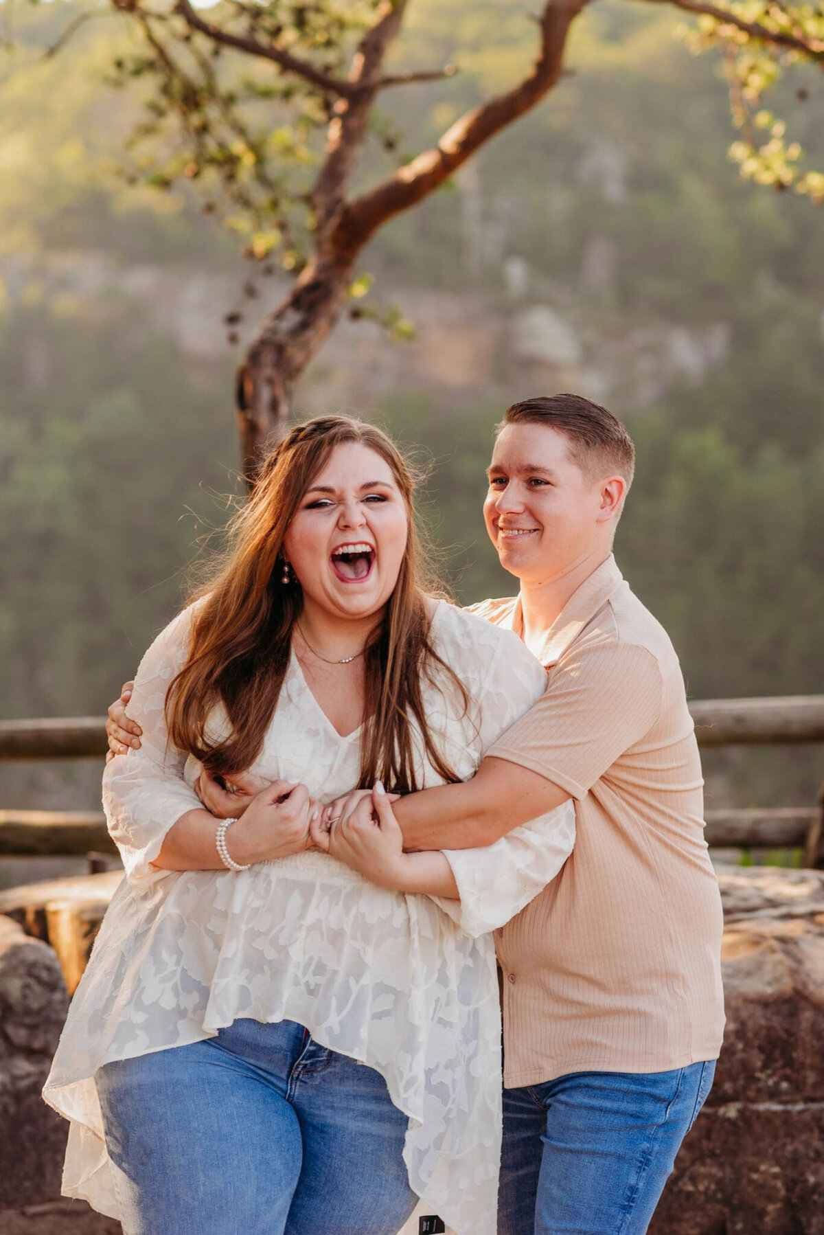 photo of woman laughing as her fiance hugs her