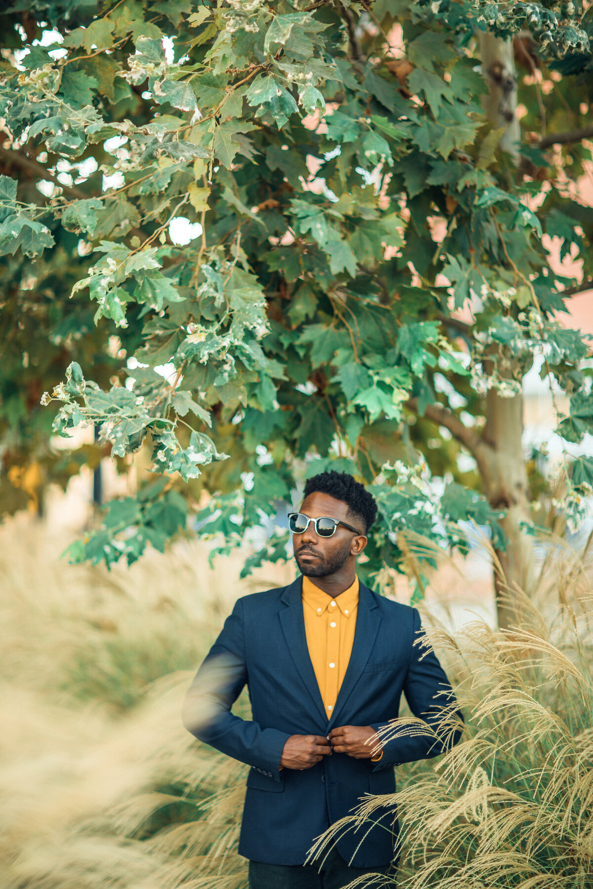 Portrait Photo Of Young Black Man Buttoning His Coat In The Middle Of Bushes Los Angeles