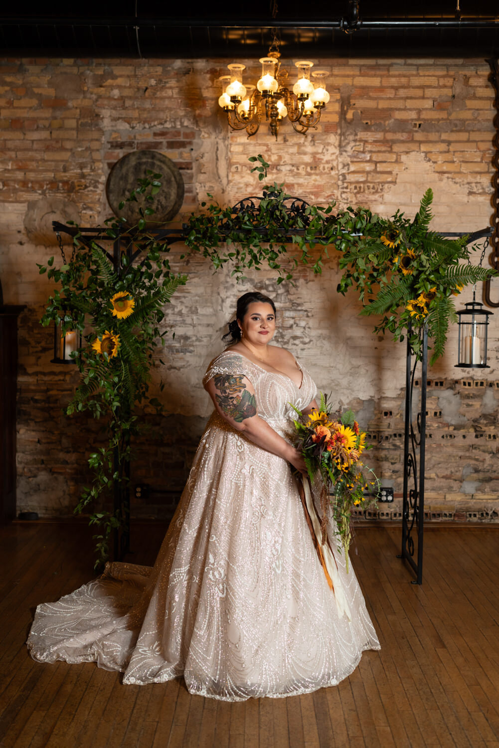 Plus size bride smiles while holding sunflowers at Kellerman's Event Center.