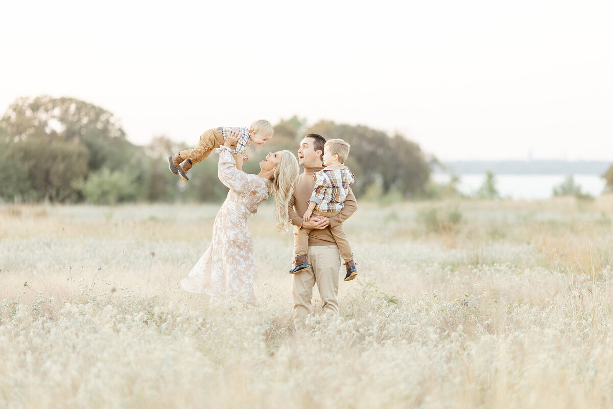 A young family of 4 playing together in the middle of a field.
