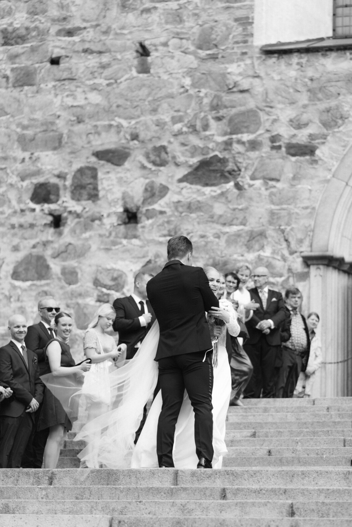 Bride and groom hugging on the stairs of Turku cathedral after their wedding ceremony. Image captured by Scandinavian wedding photographer Hannika Gabrielsson.