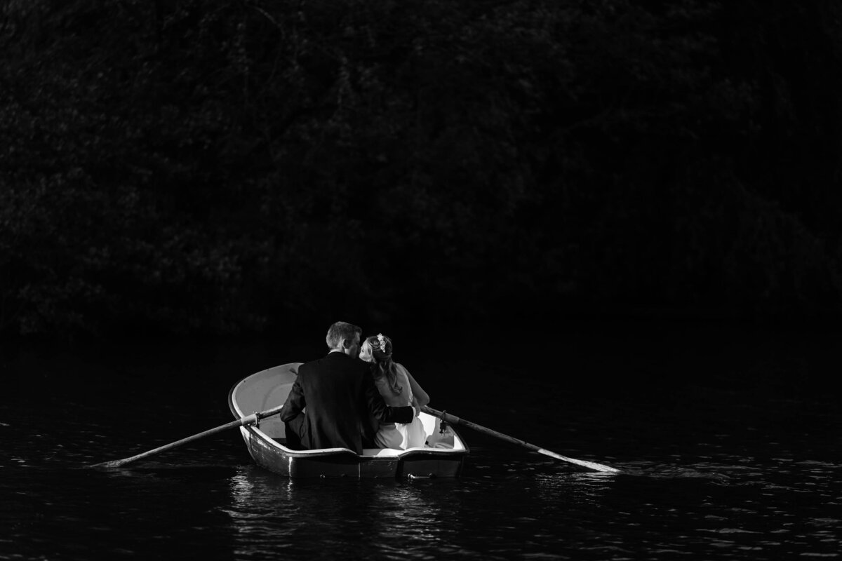 Black and white image of a bride and groom kissing in a rowing boat at Browsholme Hall