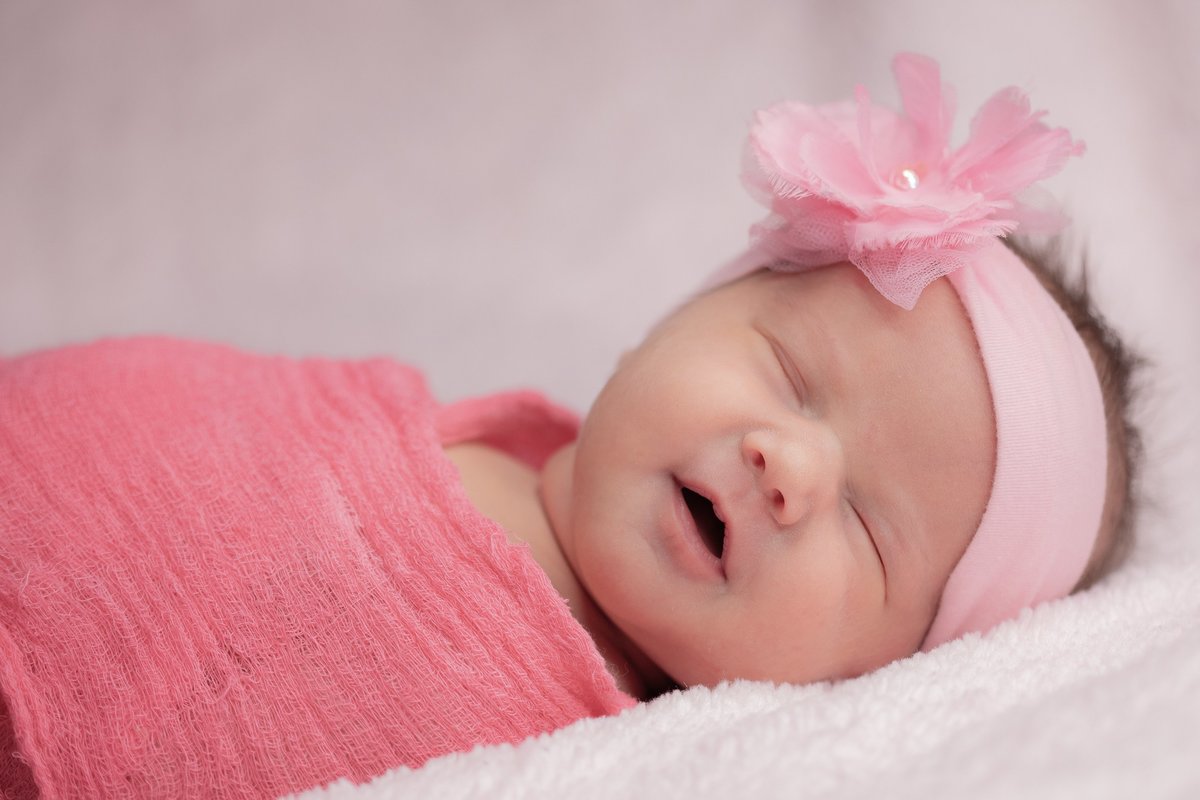 newborn in pink swaddle and headband