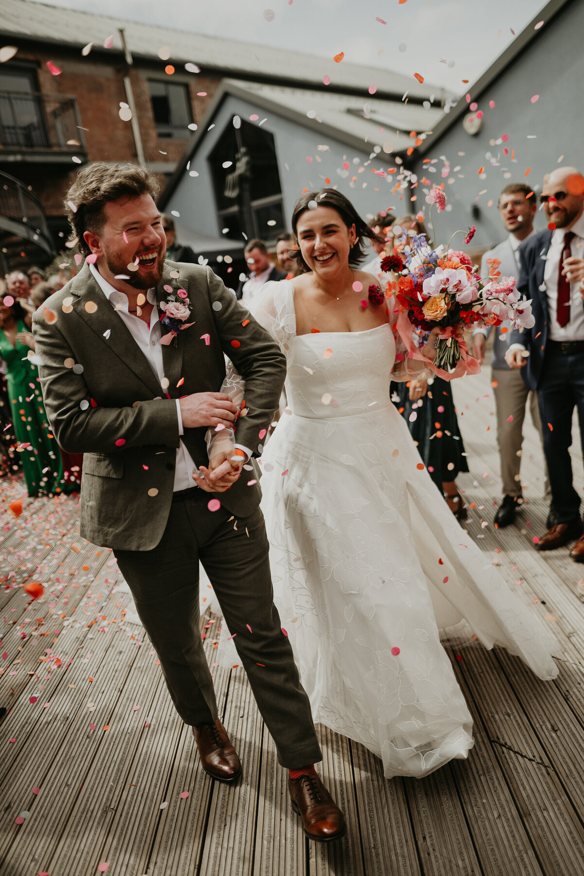 Wedding guests throw confetti at a Bride and Groom after their wedding ceremony at Paintworks in Bristol. 