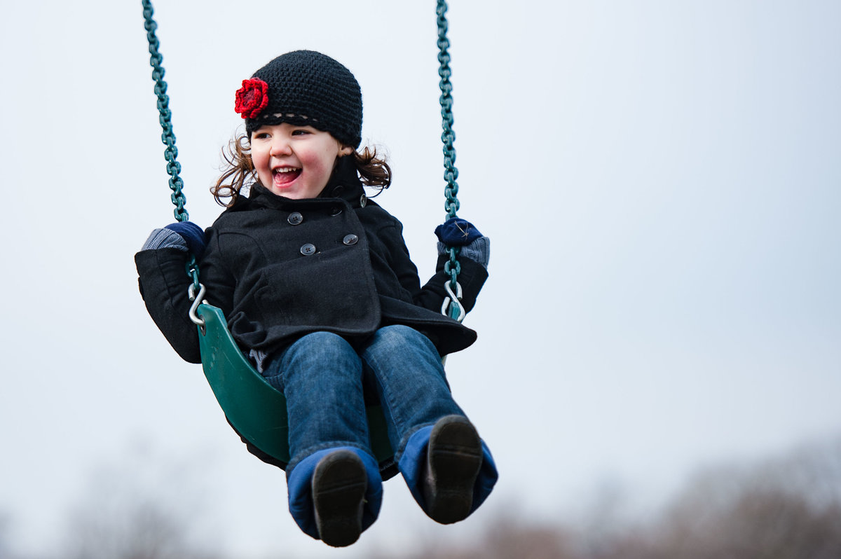 child on swing sticking tongue out