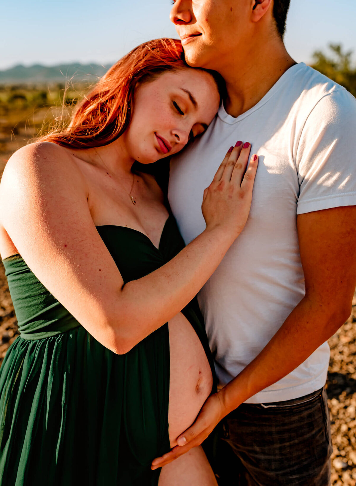 mom-to-be leaning into husband holding her baby bump captured by Arizona maternity photographer, Amber Herrera