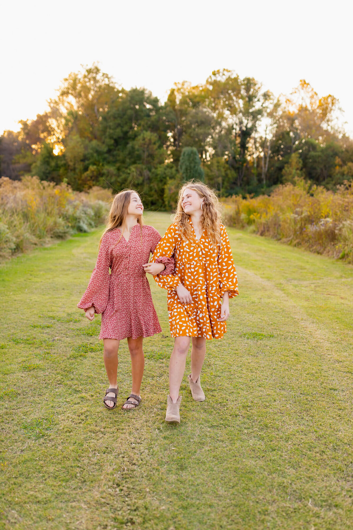 Two sisters skip arm in arm through the grass