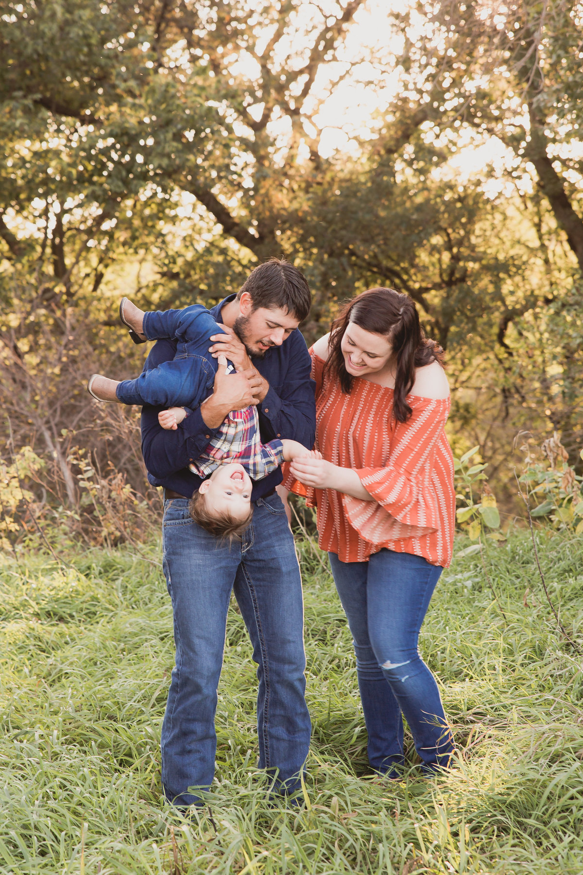 Candid lifestyle family moment playing with baby in fall foliage