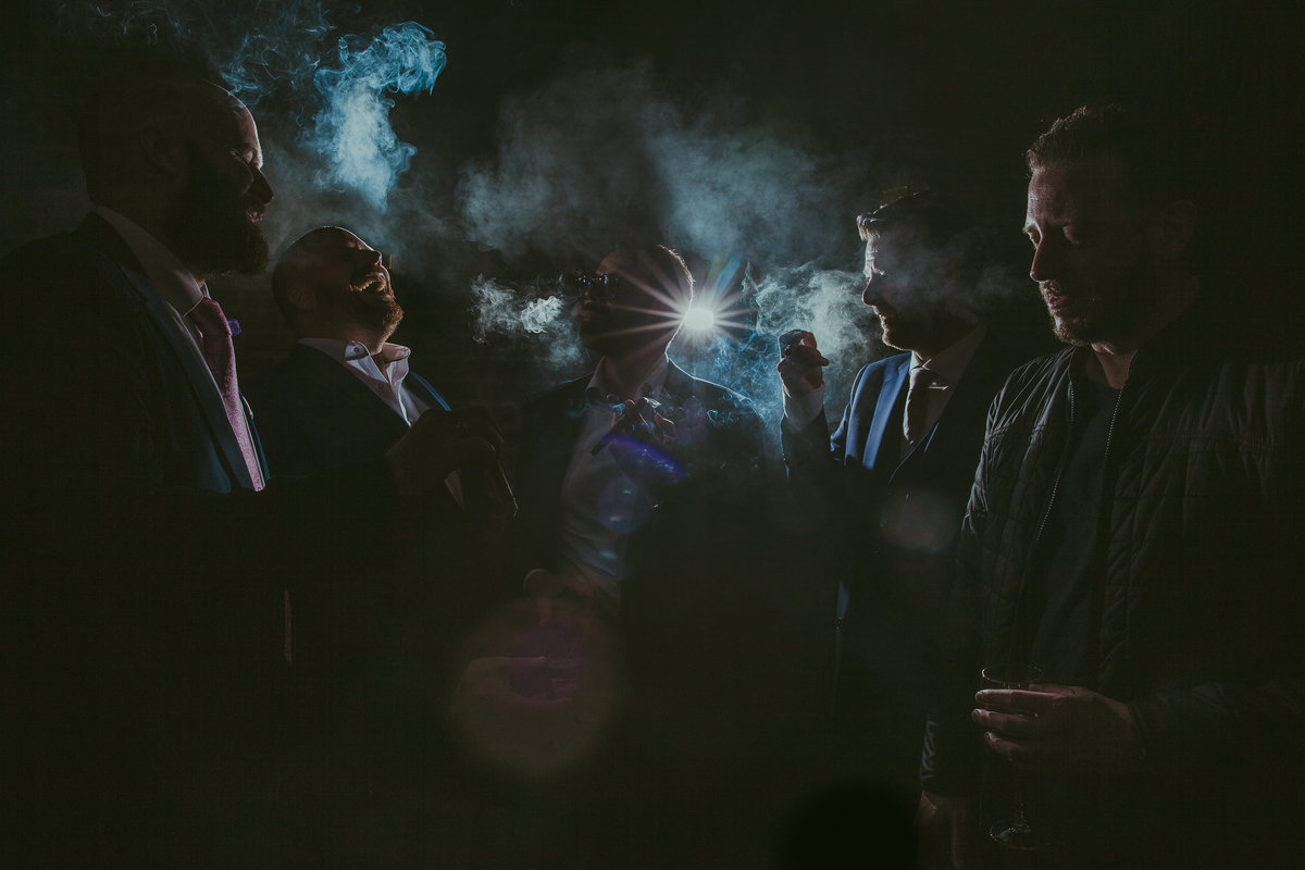 Kickass foto van bruidegom met zijn vrienden tijdens het roken van een sigaar. Smoking groom with friends. Strobe and smoke. Copyright Nanda Zee-Fritse | FOTOZEE