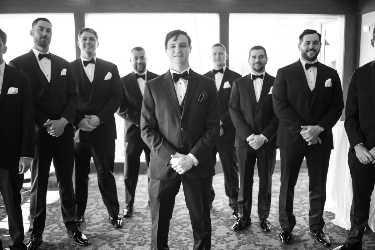 Groom smiling with groomsmen  in tuxedos