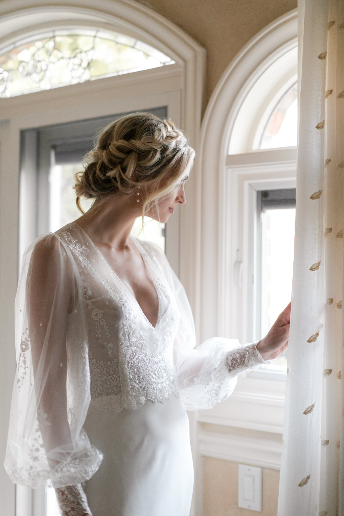 bride looking out window in wedding dress